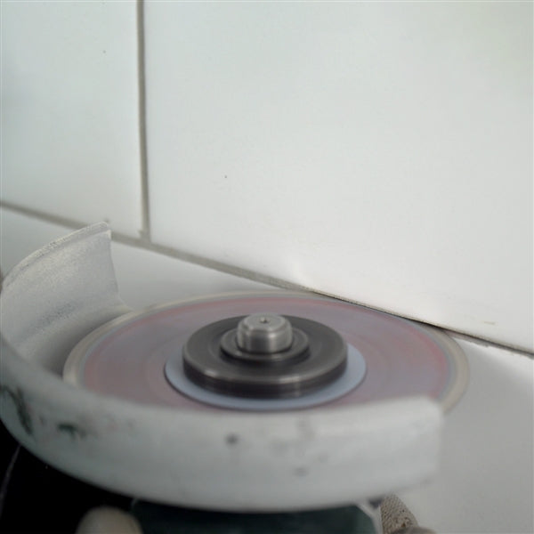 Professional tile installer using Distar Cleaner blade for grout removal