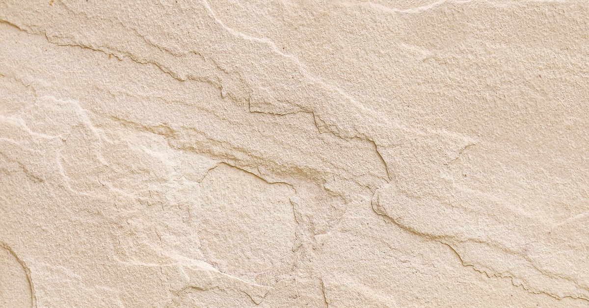 A close-up of the texture of a natural beige sandstone countertop. The texture is rigged and uneven.